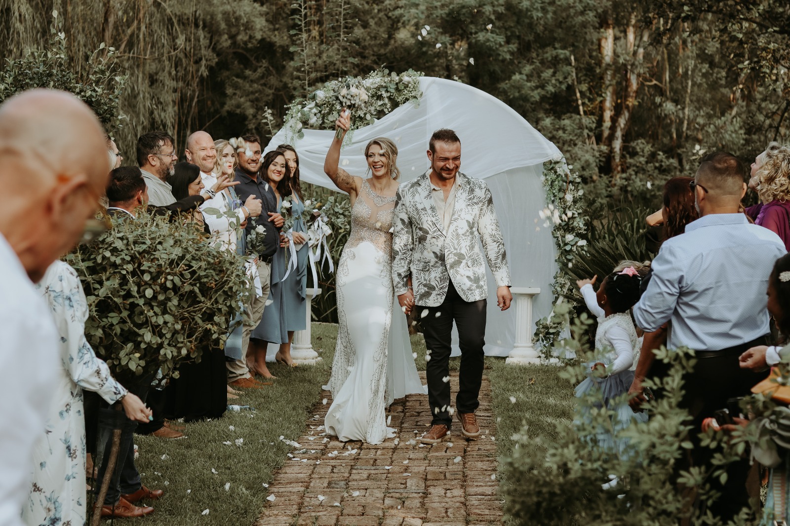 Bride and groom joyfully walk through cheering guests | Forevermore Moments