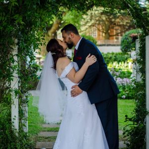 Bride and groom kissing under a green arch | Forevermore Moments Bride and groom kissing under a green arch | Forevermore Moments